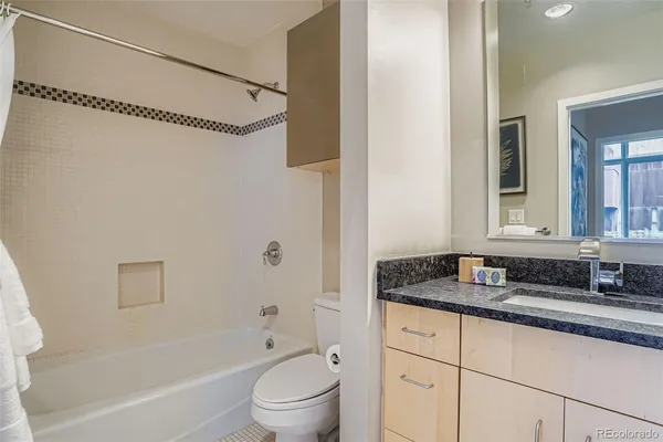 a bathroom with a granite countertop sink a toilet and bathtub