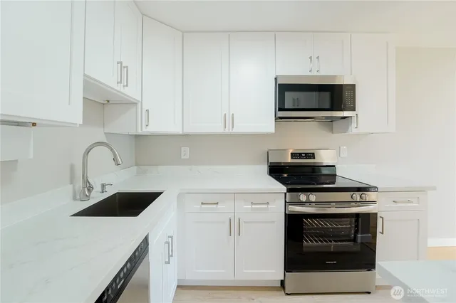 a kitchen with white cabinets and appliances