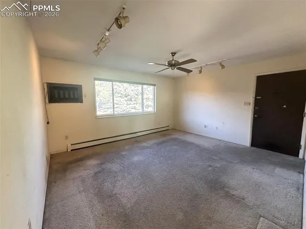 an empty room with windows and fan