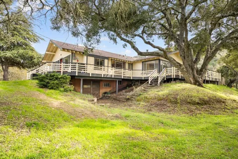 a front view of a house with a garden and trees
