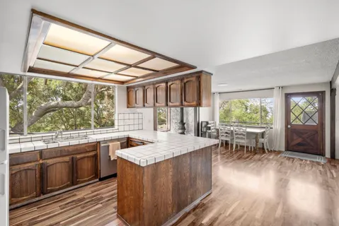 a kitchen with a stove a sink a refrigerator and wooden floor