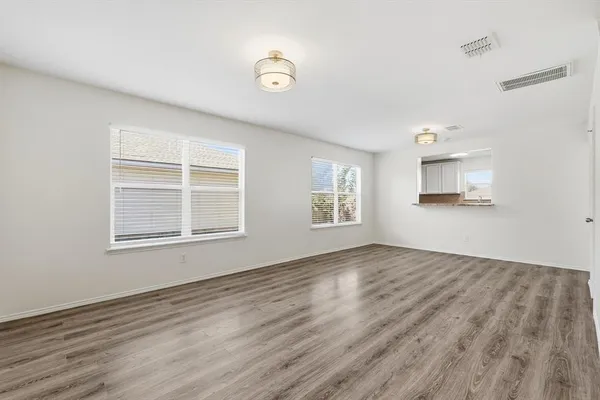a view of an empty room with a window and wooden floor