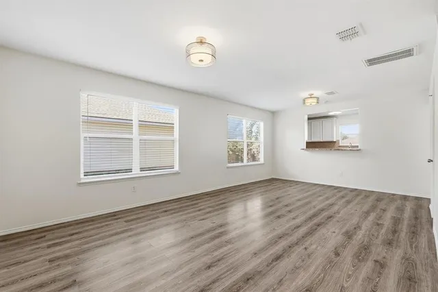 a view of an empty room with a window and wooden floor