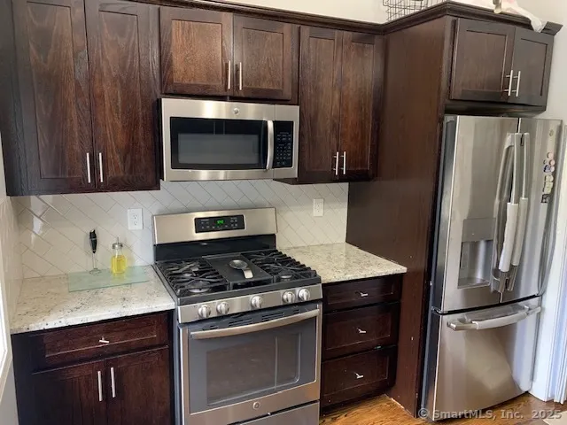 a kitchen with granite countertop wooden cabinets and stainless steel appliances