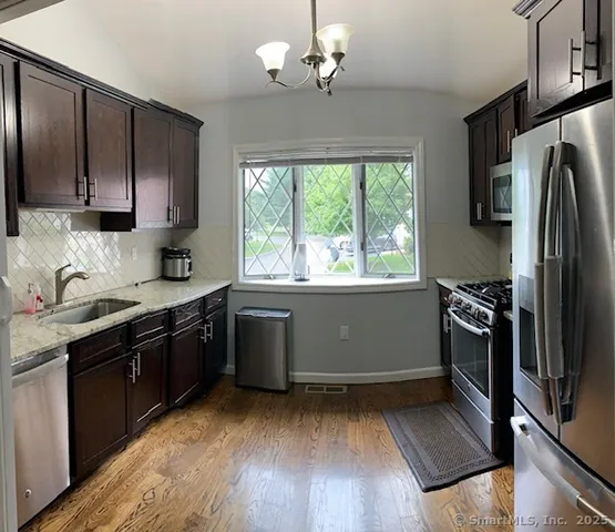 a kitchen with a sink wooden floor and stainless steel appliances