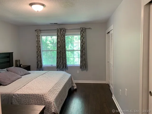 a spacious bedroom with a bed and wooden floor