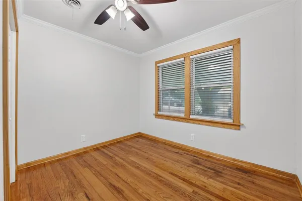 an empty room with wooden floor chandelier fan and windows