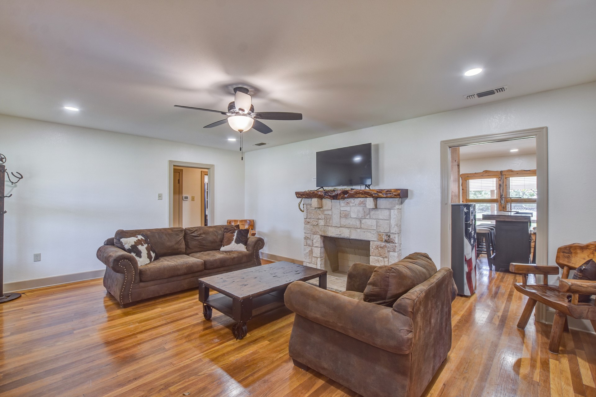 18601 County Road 214 Brookesmith, TX 76827 - Photo 28 of 39 Hunter's Cabin: Living area with a stone fireplace, light wood-style flooring, ceiling fan, and recessed lighting