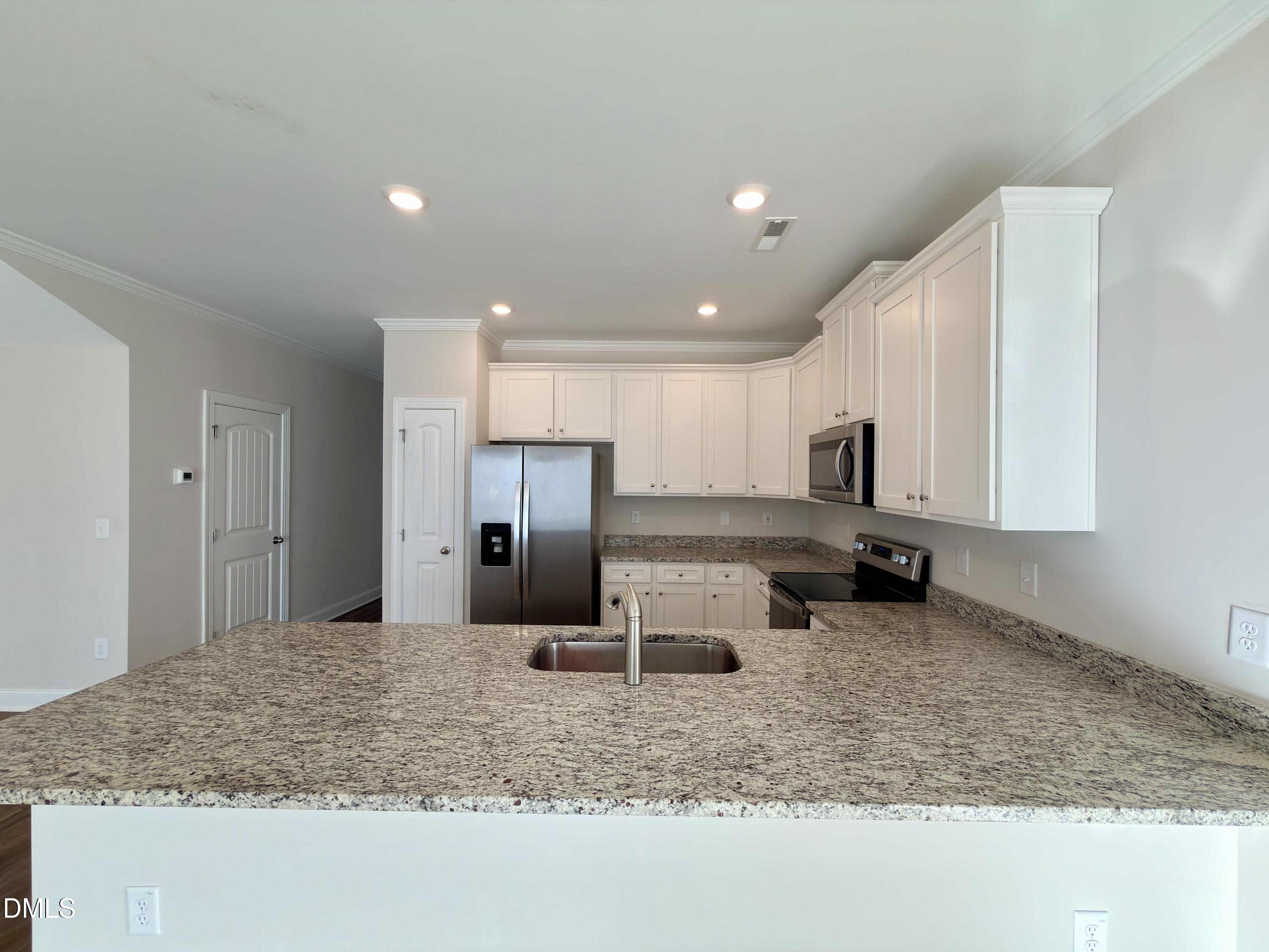 6928 Outfall Point Lane Raleigh, NC 27616 - Photo 11 of 33 a kitchen with stainless steel appliances granite countertop a sink refrigerator and cabinets