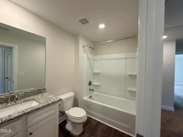 a bathroom with a granite countertop sink toilet mirror and bathtub
