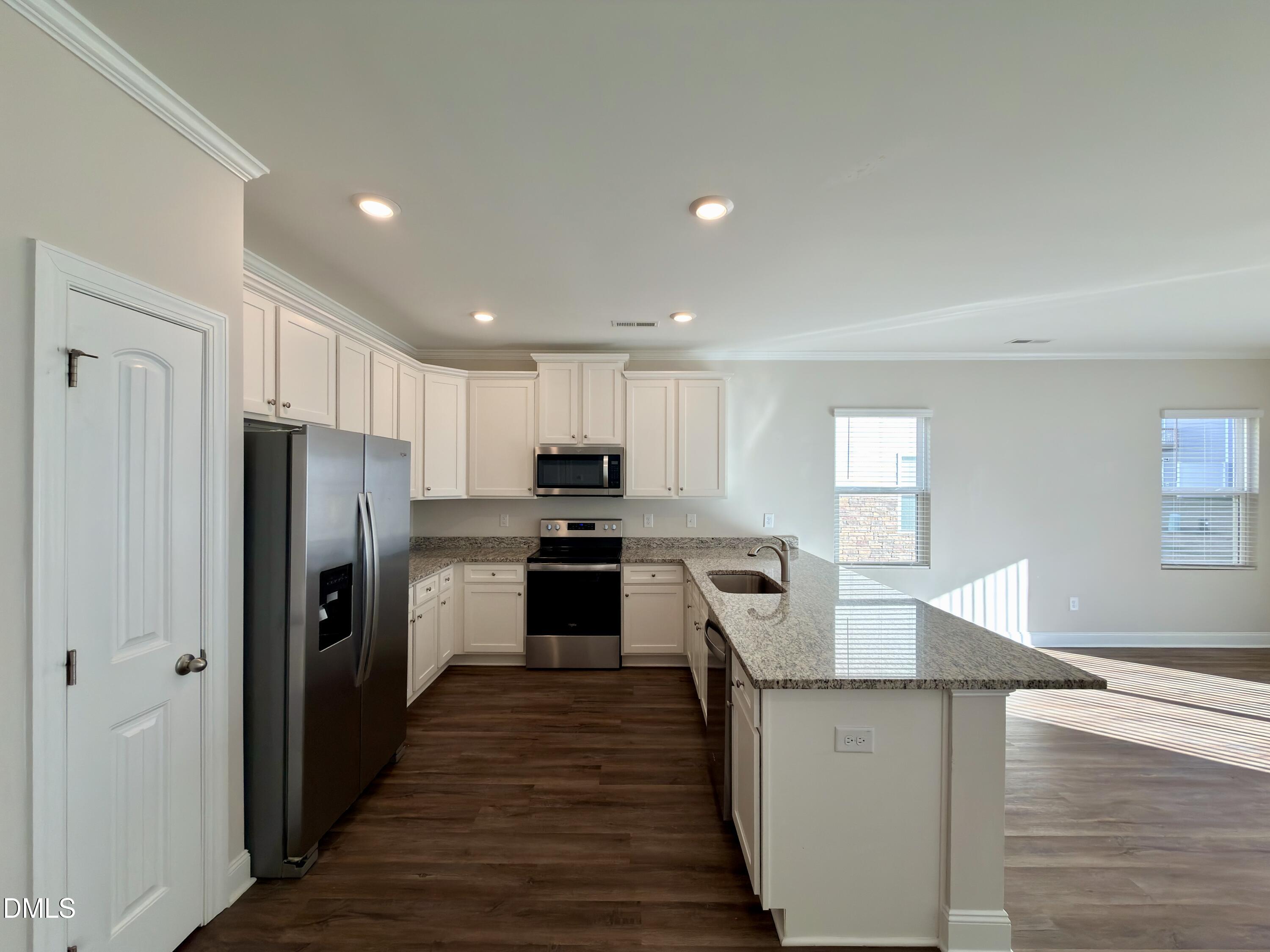 6928 Outfall Point Lane Raleigh, NC 27616 - Photo 6 of 33 a kitchen with granite countertop a refrigerator and a stove top oven
