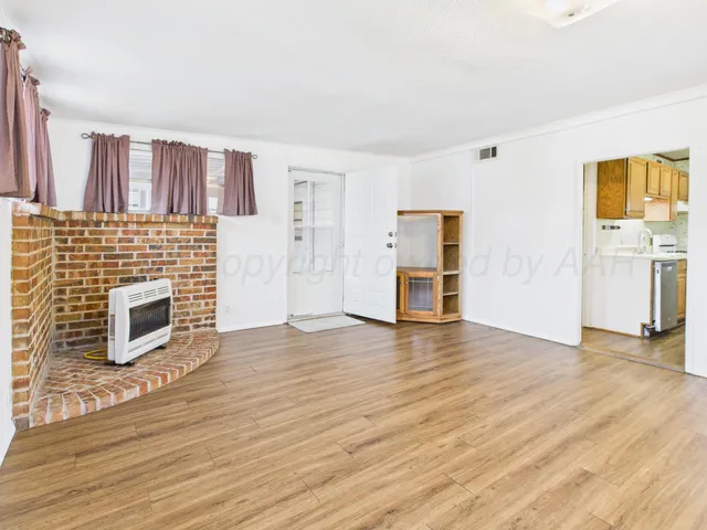 a view of a livingroom with wooden floor and a fireplace