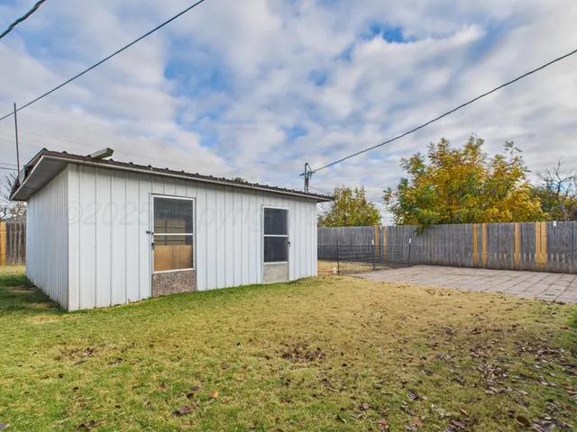 a view of a backyard with potted plants and wooden fence