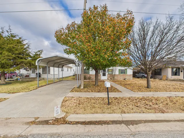 a front view of a house with a yard and trees