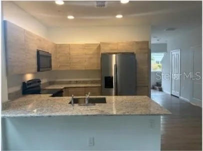 a kitchen with stainless steel appliances granite countertop a sink and a refrigerator