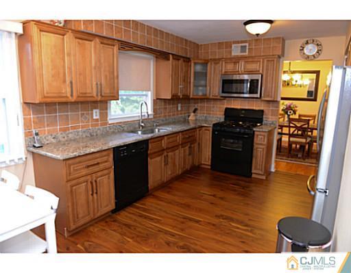 56 Meyer Road Edison, NJ 08817 - Photo 22 of 24 a kitchen with stainless steel appliances granite countertop a stove top oven a sink dishwasher and wooden cabinets