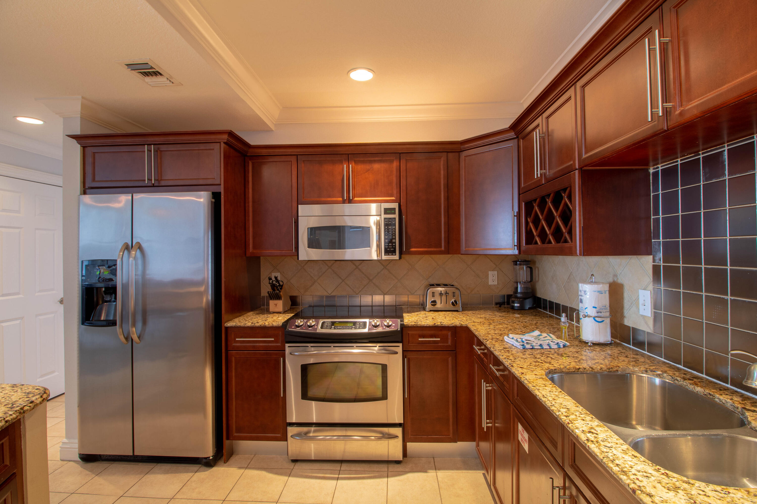 10 Harbor Boulevard, Unit E707H Destin, FL 32541 - Photo 9 of 28 a kitchen that has a sink wooden cabinets and stainless steel appliances