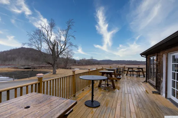 a view of a roof deck with table and chairs a barbeque with wooden floor and fence