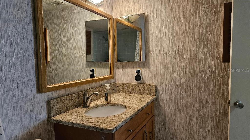 4600 98th Way North, Unit 210 St. Petersburg, FL 33708 - Photo 21 of 33 a bathroom with a granite countertop sink and a mirror