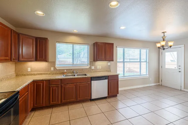 a large kitchen with granite countertop a sink window and cabinets