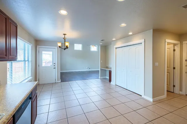 an empty room with kitchen and chandelier fan