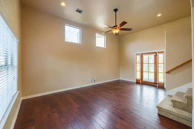 a view of an empty room with a window and wooden floor