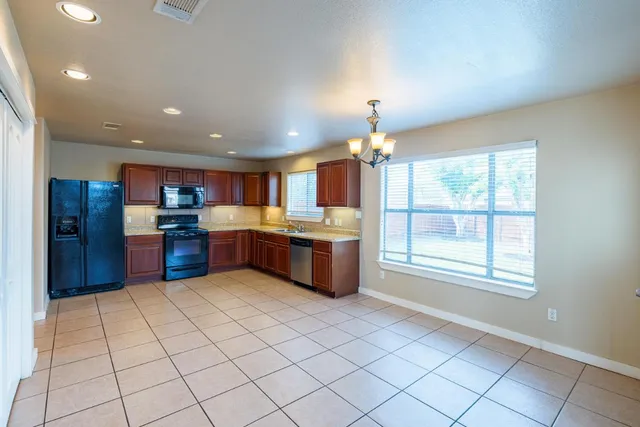 a kitchen with stainless steel appliances kitchen island granite countertop a refrigerator and a sink