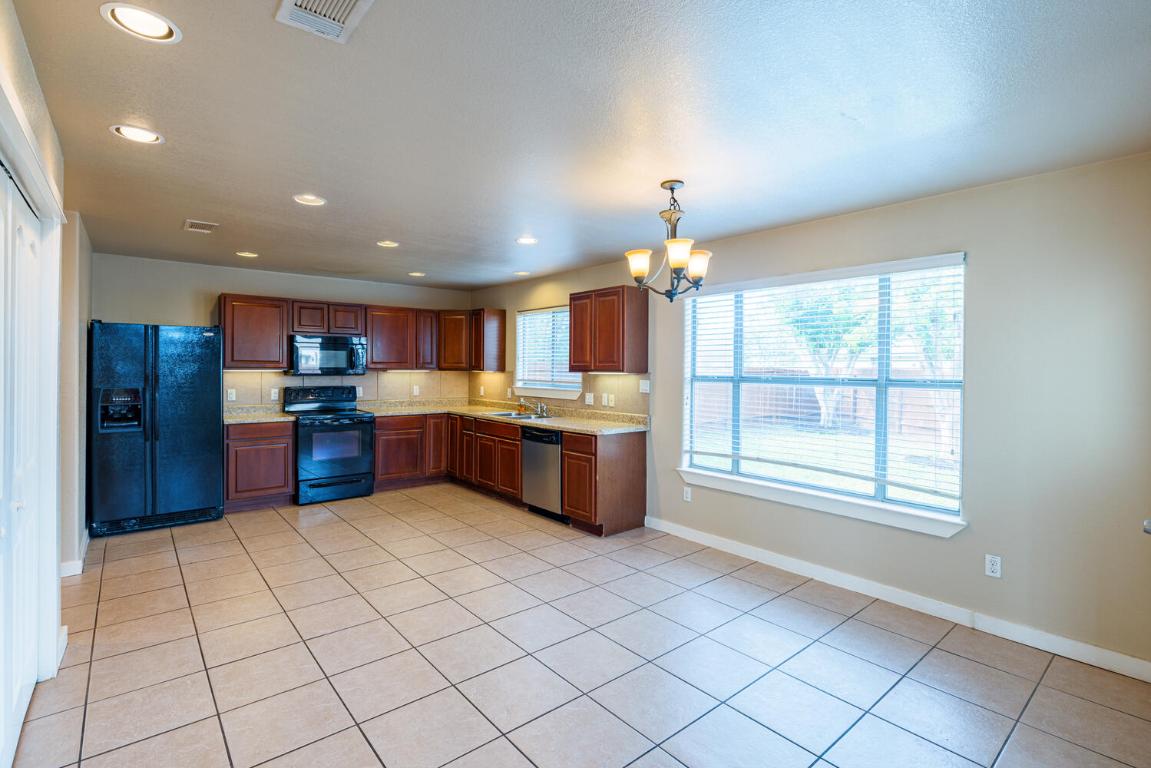 2102 Laura Court Round Rock, TX 78681 - Photo 7 of 32 a kitchen with stainless steel appliances kitchen island granite countertop a refrigerator and a sink