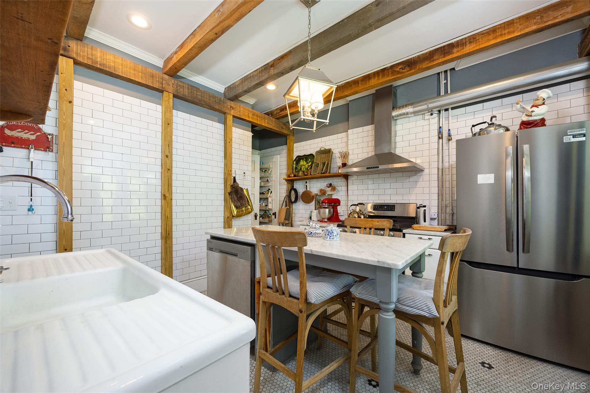 111 South Hamilton Street Poughkeepsie, NY 12601 - Photo 11 of 33 Kitchen featuring wood-finish ceiling beams, white subway tile walls, stainless steel appliances, a center island with a stone-finish countertop, and decorative floor tiling