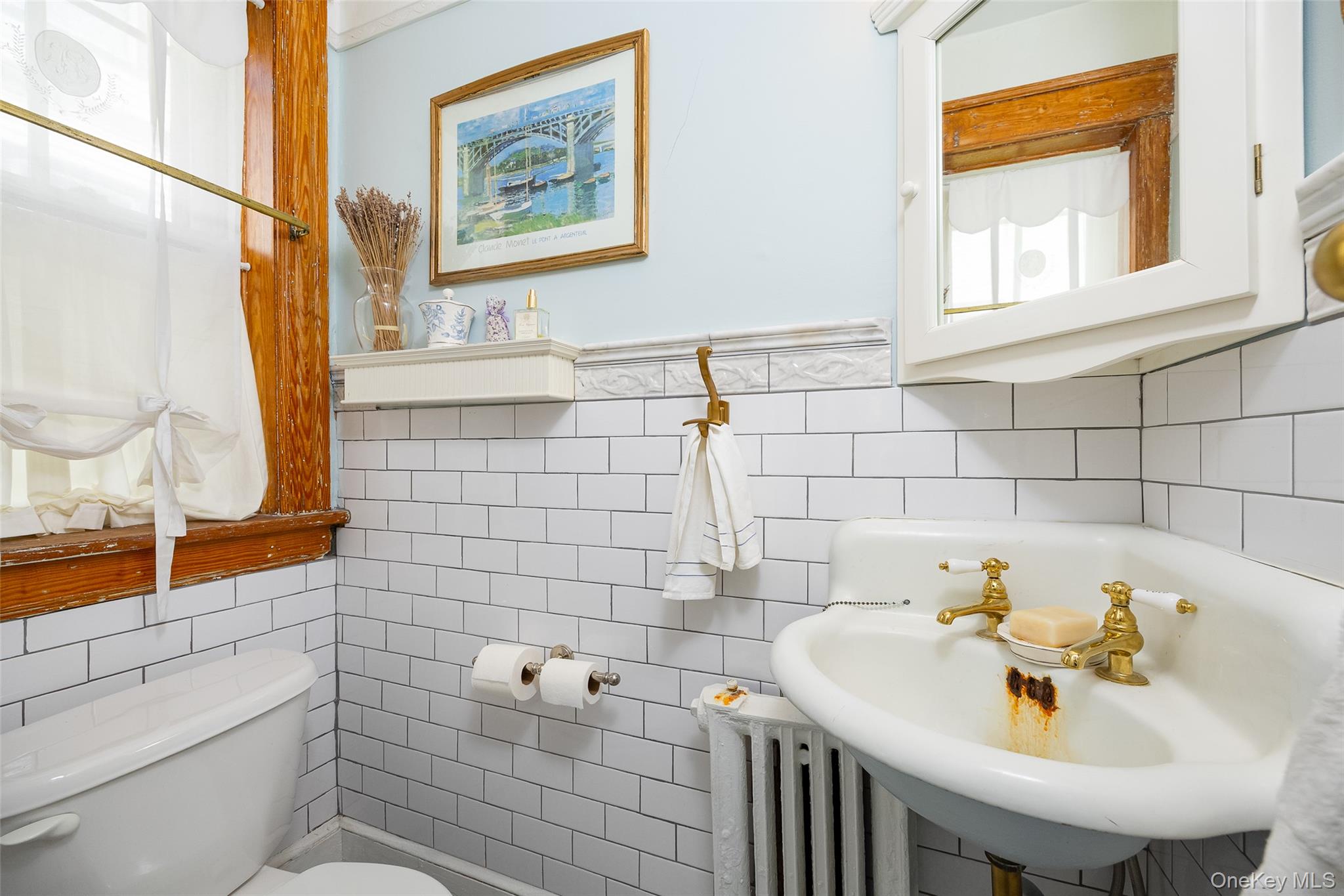 111 South Hamilton Street Poughkeepsie, NY 12601 - Photo 14 of 33 Bathroom featuring white subway tile walls, a pedestal sink with brass-finish fixtures, a wall-mounted medicine cabinet, a window with natural wood trim, and light blue painted walls