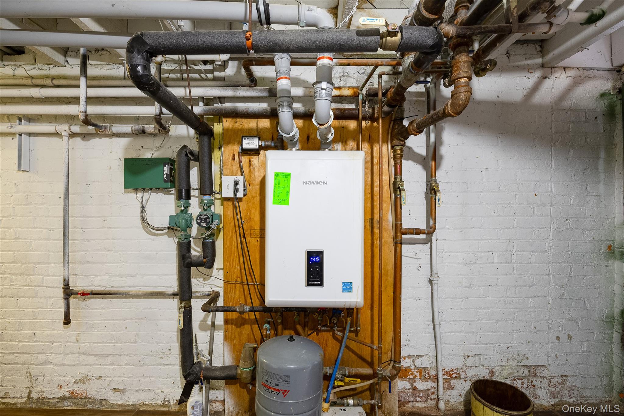 111 South Hamilton Street Poughkeepsie, NY 12601 - Photo 25 of 33 Utility area featuring a wall-mounted tankless water heater, extensive plumbing infrastructure, a pressure expansion tank, and exposed overhead piping