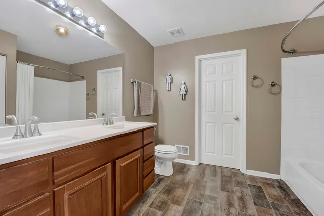 a spacious bathroom with a double vanity sink toilet and shower