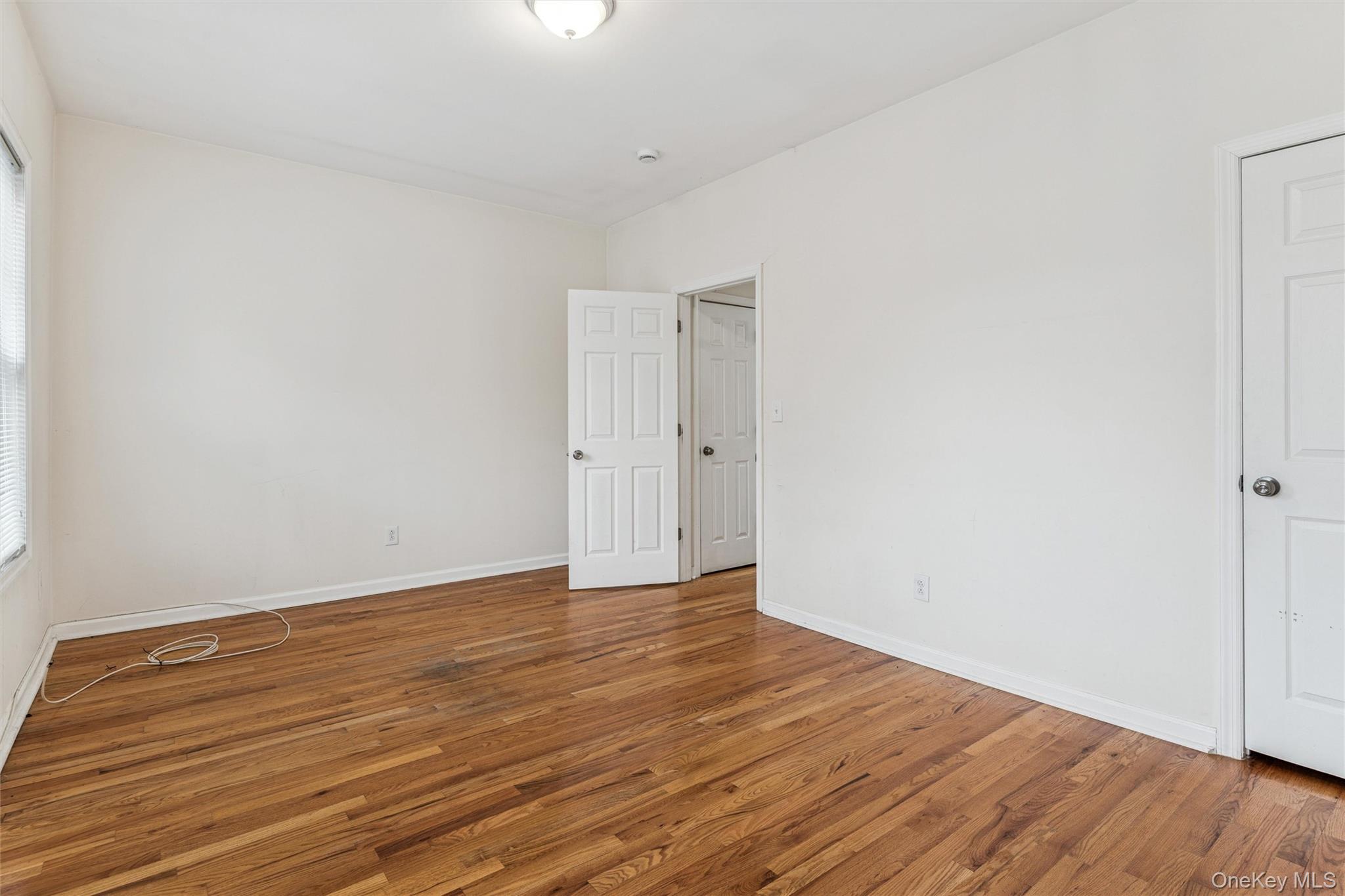 91-25 90th Street Queens, NY 11421 - Photo 18 of 30 Empty room with wood finished floors and baseboards