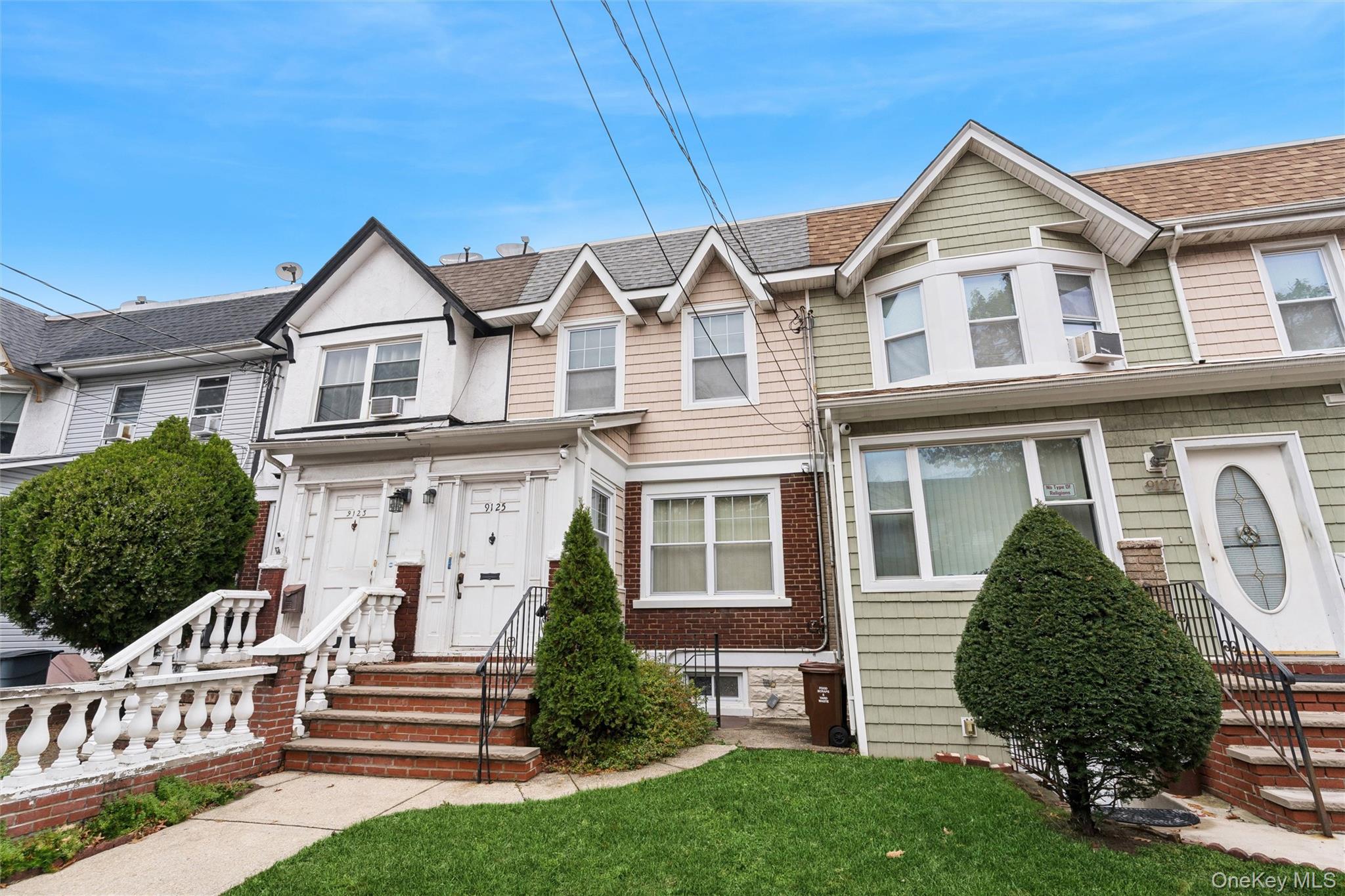 91-25 90th Street Queens, NY 11421 - Photo 2 of 30 Traditional-style house featuring roof with shingles and a front lawn