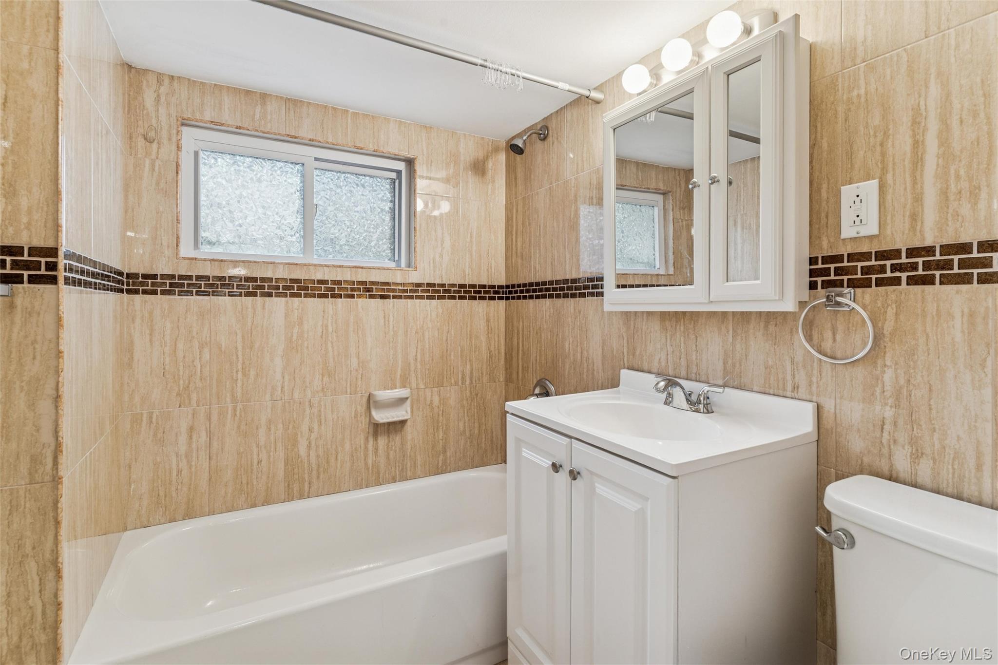 91-25 90th Street Queens, NY 11421 - Photo 25 of 30 Full bathroom featuring vanity, shower / bathtub combination, tile walls, and plenty of natural light