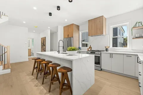 a kitchen with white cabinets and chairs