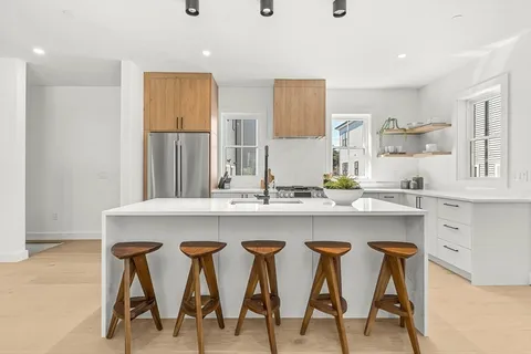 a kitchen with stainless steel appliances granite countertop chairs and white cabinets