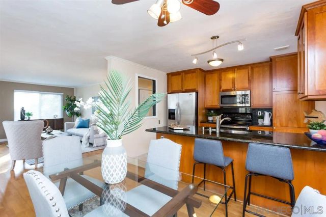 a kitchen with stainless steel appliances granite countertop a stove refrigerator a dining table and chairs with wooden floor