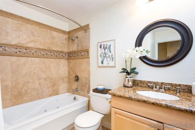 a bathroom with a granite countertop toilet a sink and a bathtub