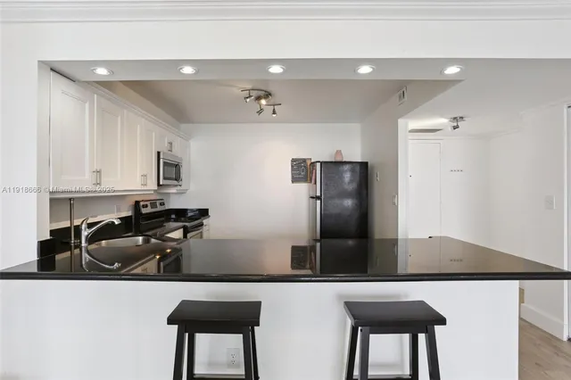 a kitchen with granite countertop white cabinets and stainless steel appliances