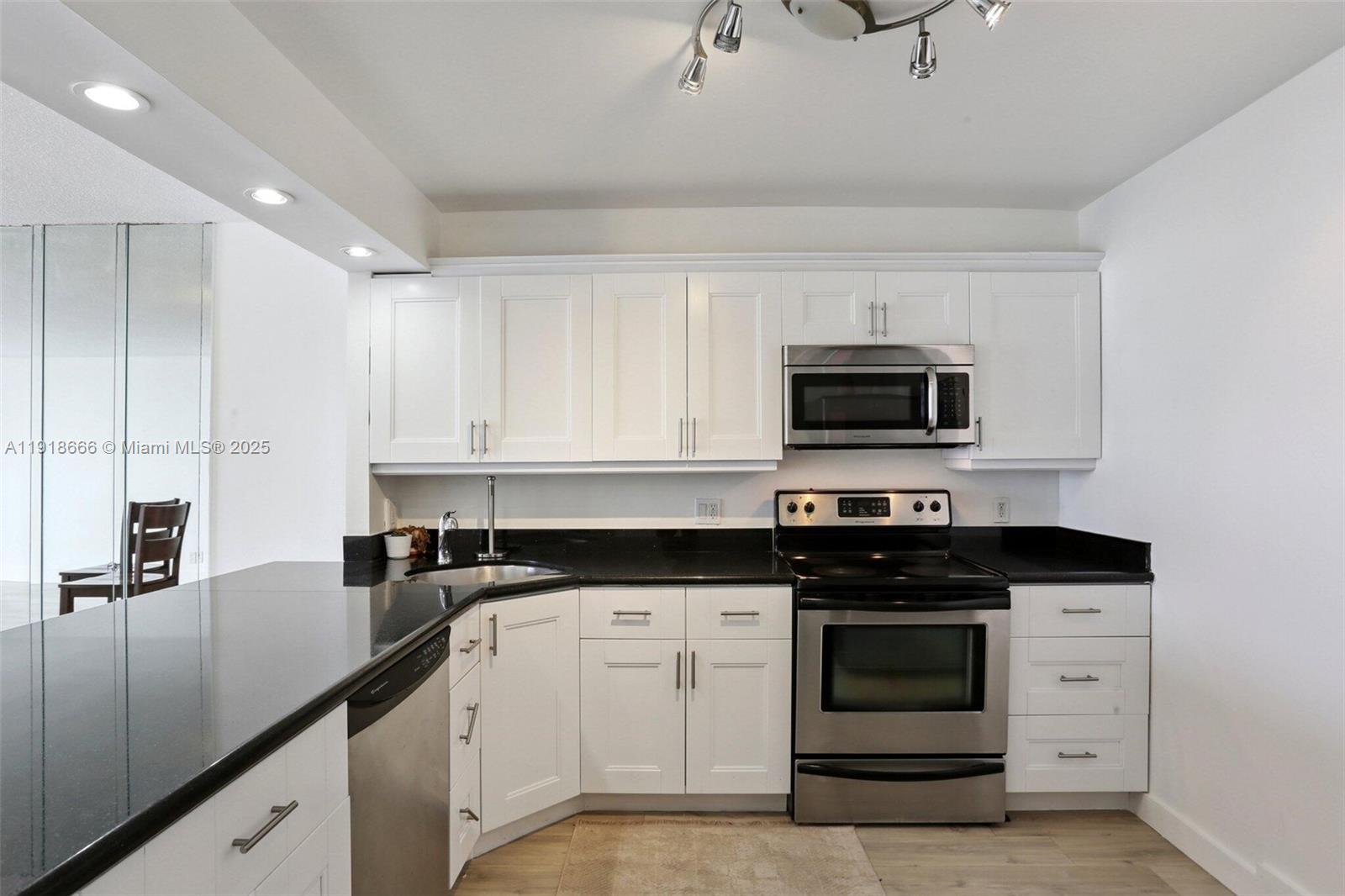427 Golden Isles Drive, Unit 11F Hallandale Beach, FL 33009 - Photo 8 of 24 a kitchen with granite countertop white cabinets and stainless steel appliances