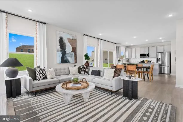 a living room with furniture kitchen view and a large window