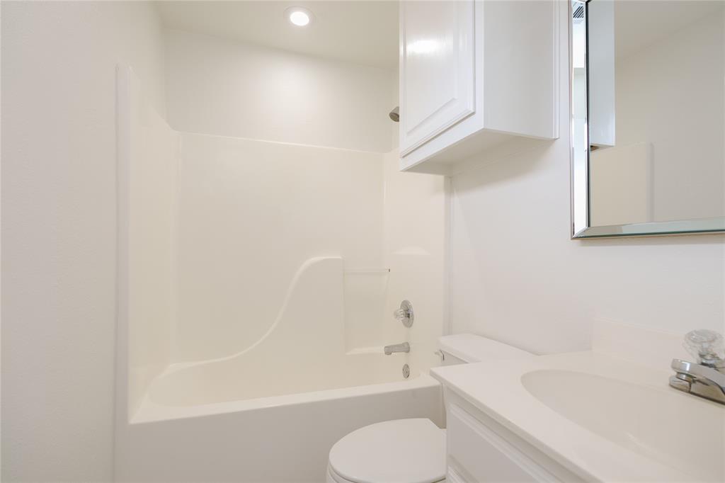 364 Parker Road, Unit A Van Alstyne, TX 75495 - Photo 27 of 39 Second primary suite Bathroom, featuring a white integrated tub and shower unit, a white vanity with an integrated sink, a mirrored medicine cabinet, a wall-mounted cabinet, and recessed ceiling lighting