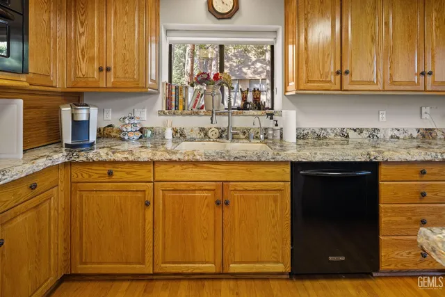 a kitchen with stainless steel appliances granite countertop wooden cabinets a sink and a large window