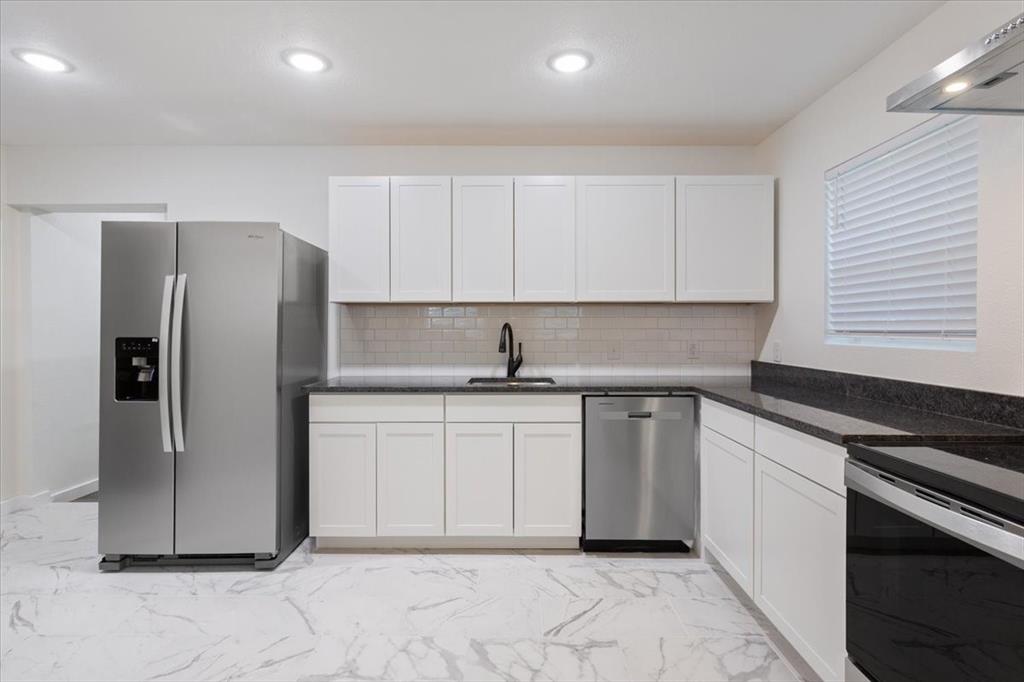 108 Private Road Whitney, TX 76692 - Photo 15 of 36 Modern kitchen featuring white shaker cabinetry, dark countertops, a subway tile backsplash, stainless steel appliances, and large format marble-look tile flooring