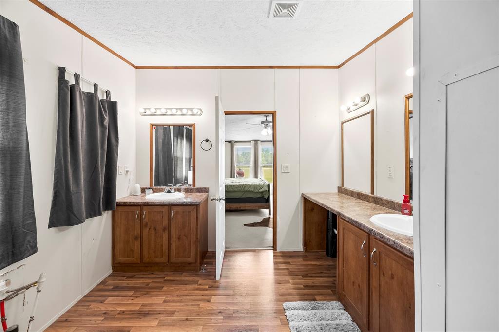 10020 Lavender Road Crowley, TX 76036 - Photo 14 of 29 Full bathroom with two vanities, a textured ceiling, connected bathroom, dark wood-style floors, and crown molding