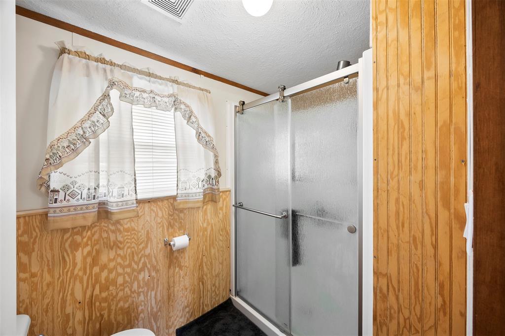 10020 Lavender Road Crowley, TX 76036 - Photo 19 of 29 Full bath with a stall shower, a textured ceiling, wooden walls, and wainscoting