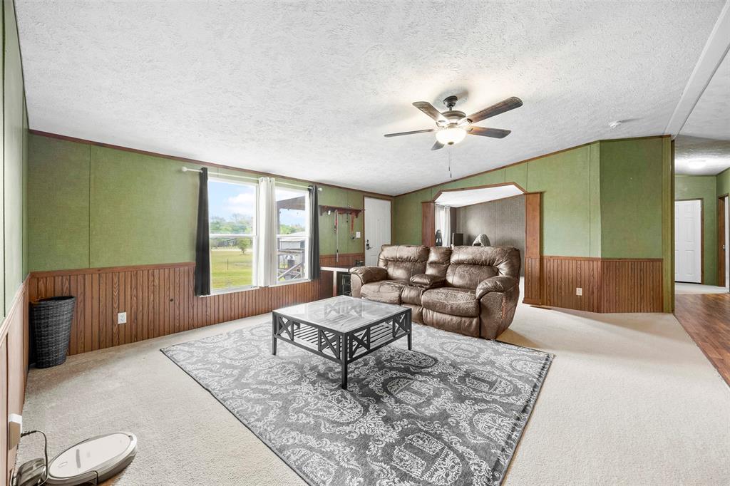 10020 Lavender Road Crowley, TX 76036 - Photo 7 of 29 Carpeted living area featuring wood walls, a wainscoted wall, and ceiling fan