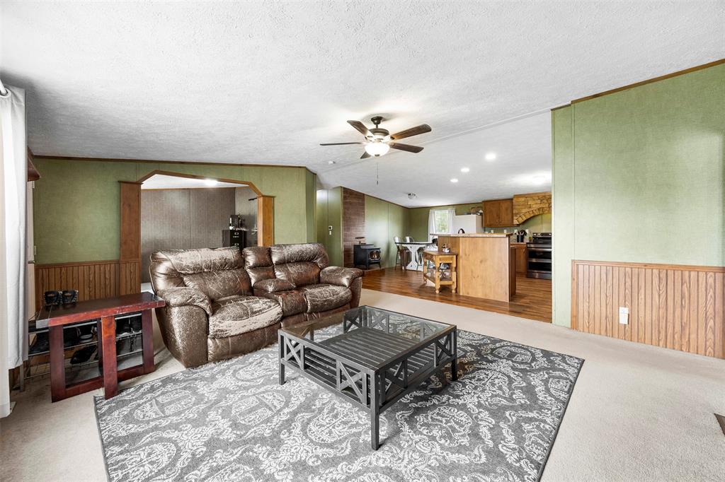 10020 Lavender Road Crowley, TX 76036 - Photo 8 of 29 Living room featuring a wainscoted wall, wood walls, light colored carpet, arched walkways, and a ceiling fan