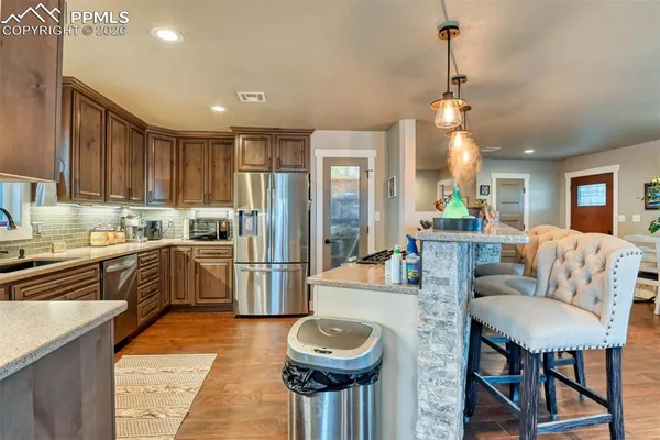 a living room with stainless steel appliances furniture a rug kitchen view and a chandelier
